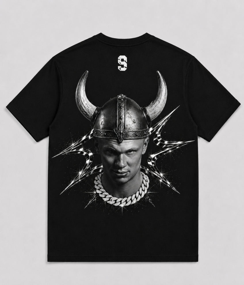 A black short-sleeve t-shirt with a large graphic print on the front showing a man in a horned Viking helmet, lightning bolts, and a silver chain necklace. A small white stylized '9' logo is printed on the inside of the collar. FOOTBALL