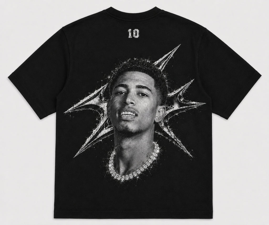 A black short-sleeve t-shirt featuring a large black-and-white graphic print of a man's portrait with a diamond chain necklace and a starburst design on the back. The number '10' is printed in white near the upper neckline. JUDE BELLINGHAM 
