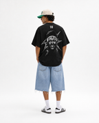 A model shown from the back wearing a black oversized t-shirt with a large graphic print of a face and the word 'NEYMAR' on the back, paired with light blue denim shorts, white socks, and black-and-white sneakers against a plain white background.