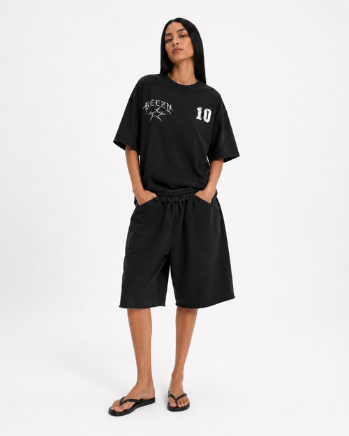 A woman modeling a black oversized t-shirt and matching black shorts set. The t-shirt features a white graphic on the left chest with the word 'KEEZY' and a star design, and the number '10' on the right chest. FOOTBALL JUDE 