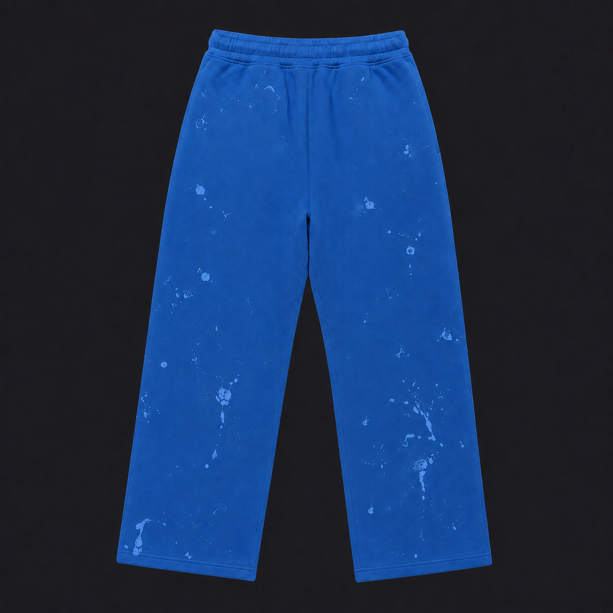 Bright blue sweatpants with a white splatter or bleach-splatter pattern, laid flat against a solid black background.