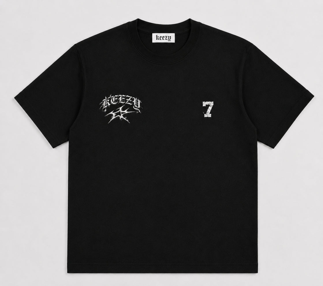 A black short-sleeve crewneck t-shirt with a white distressed graphic on the left chest featuring the word 'KEZEY' and a star, and a distressed white number '7' on the right chest. The inner neck label shows the brand 'keazy'.