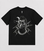 A black short-sleeve t-shirt with a large black-and-white graphic print on the front showing a stylized face with a goat horn and a silver chain necklace, with a small white number 7 printed above the collar.